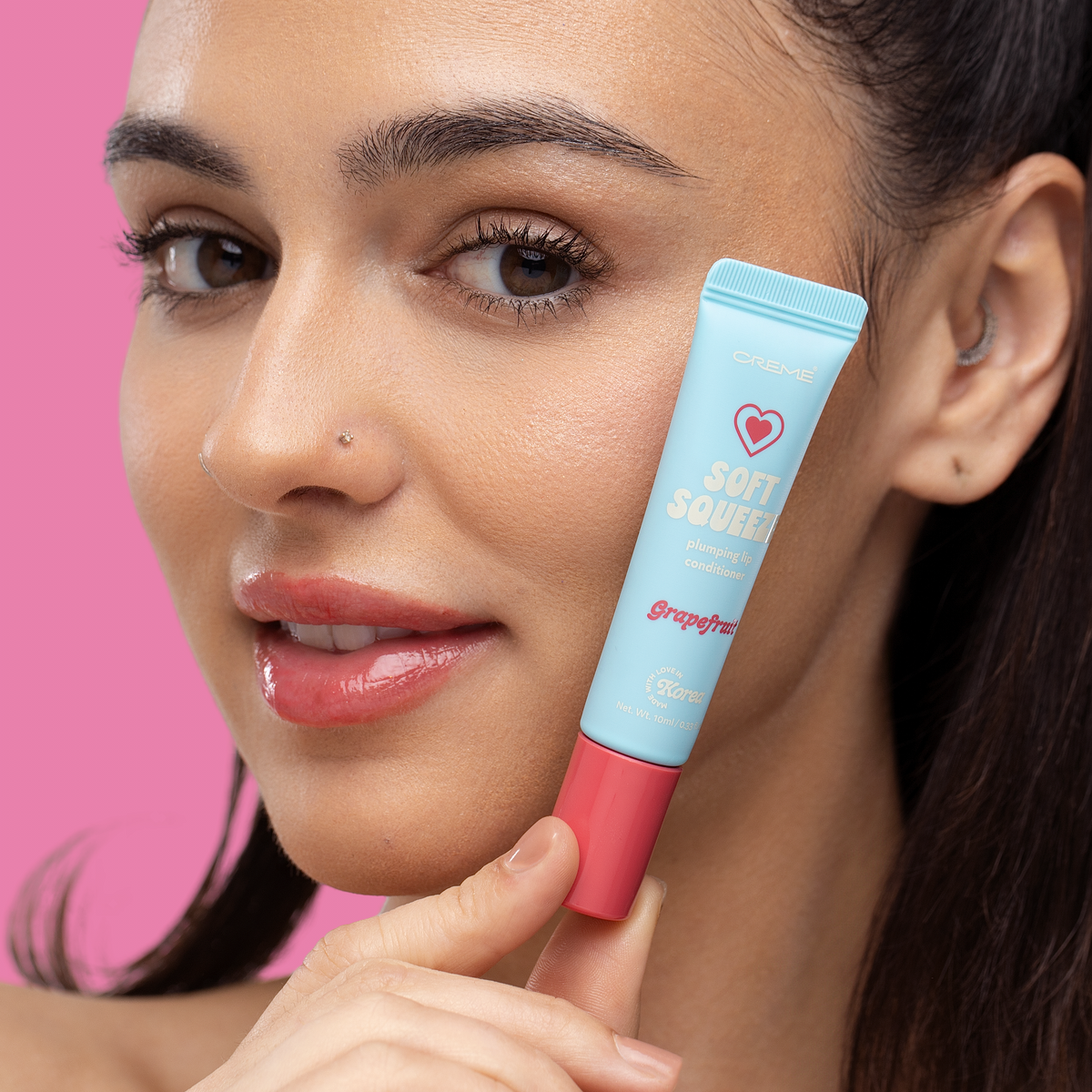 Soft Squeeze Lip Conditioner — Grapefruit — model holding the tube beside her face
