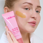 Heat Up, Glow Up Wash Off Mask — model with a golden mask swatch on her cheek holding the tube
